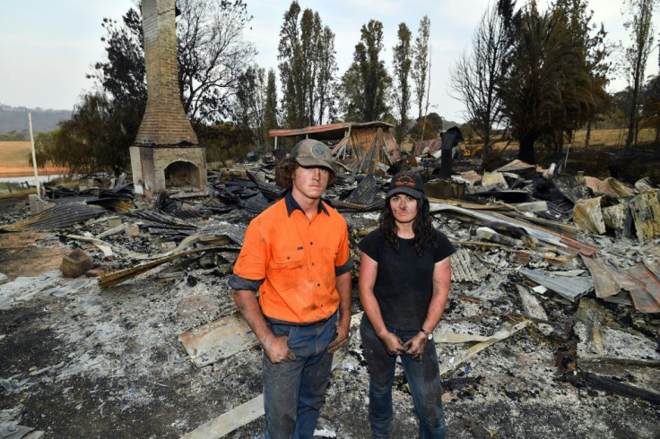 Brother and sisters Jesse and Kiahan Bellchambers stand in front of the charred ruins of their home in Batlow, in Australia's New South Wales state