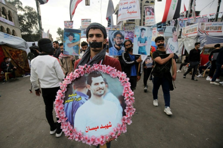 An Iraqi anti-government demonstrator carries a wreath with a picture of a killed fellow protester during a march in Baghdad's Tahrir square