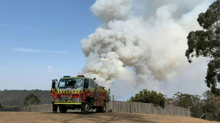 Firefighters in Penrose, New South Wales, work to protect a house from an approaching fire.