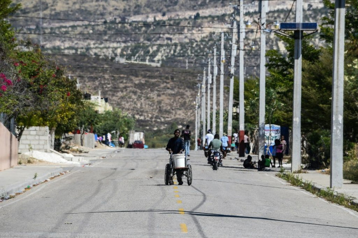 A man carries water on a wheelchair on a street in the Haitian city of Croix des Bouquets; 10 years after the devastating quake of 2010, life is little improved for many Haitians