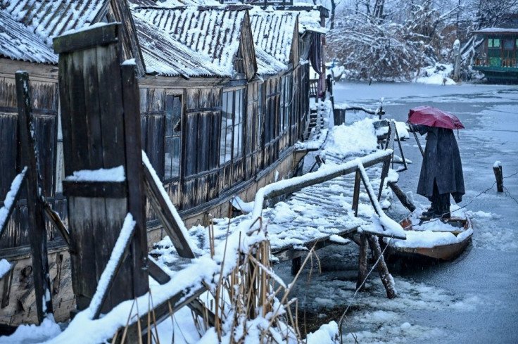 A man removes snow from his boat on the banks of Dal Lake in Srinagar in India