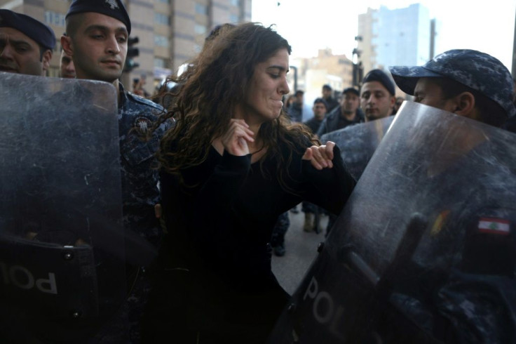 A Lebanese anti-corruption protester is surrounded by riot police during a demonstration in downtown Beirut