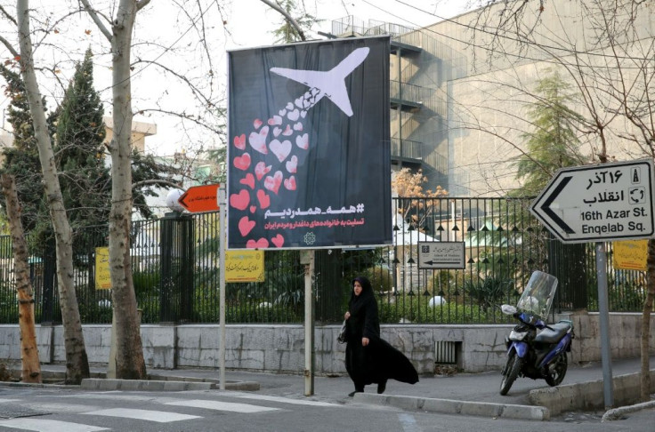 An Iranian woman walks beneath a poster outside Amirkabir University honouring the victims of the Ukrainian passenger jet accidentally shot down by Tehran