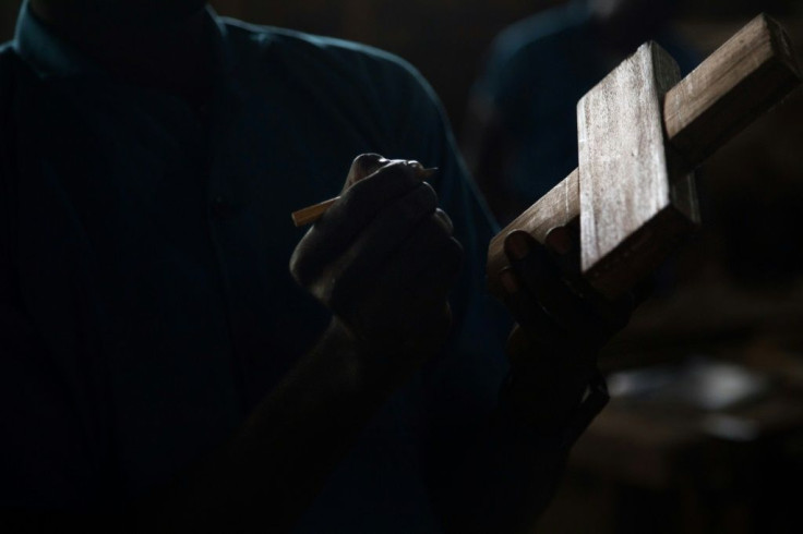 A former child soldier on a carpentry course draws a cutout on a piece of wood