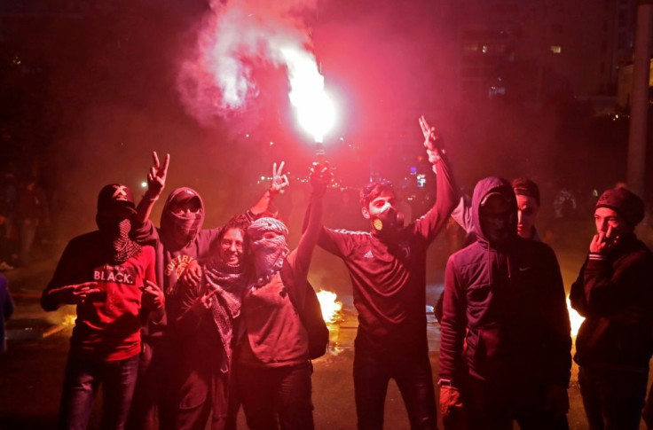 Lebanese anti-government protesters light a flare during ongoing demonstrations in Lebanon's capital Beirut on January 15