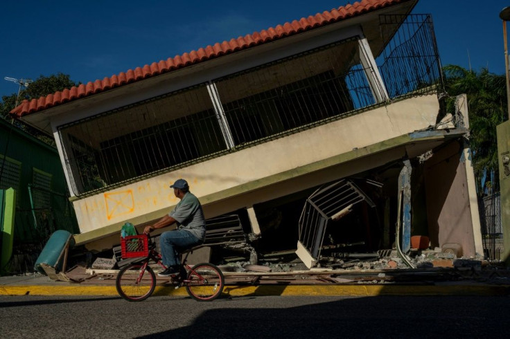 A man rides his bicycle past a collapsed house in Guanica, Puerto Rico on January 15, 2020, after a powerful earthquake hit the island