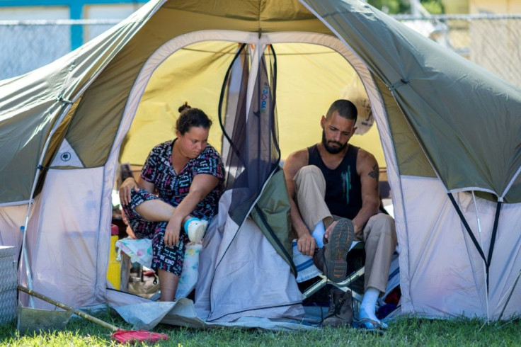 Juan Santiago gets ready for work as his wife, Solmely Velazquez looks on in their tent in a baseball field in Guanica, Puerto Rico on January 15, 2020, after a powerful earthquake hit the island