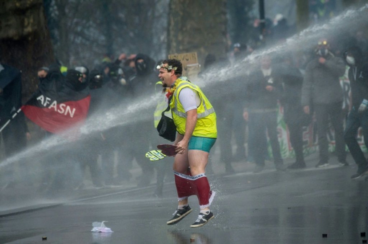A 'Yellow Vest' protester is soaked by a police water cannon