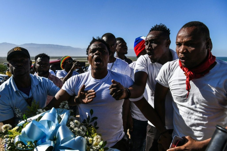 Protestors shout anti-government slogans outside a mass graveyard during the commemorative ceremonies of Haiti's 10th earthquake anniversary on the outskirts of Port-au-Prince, on January 12, 2020