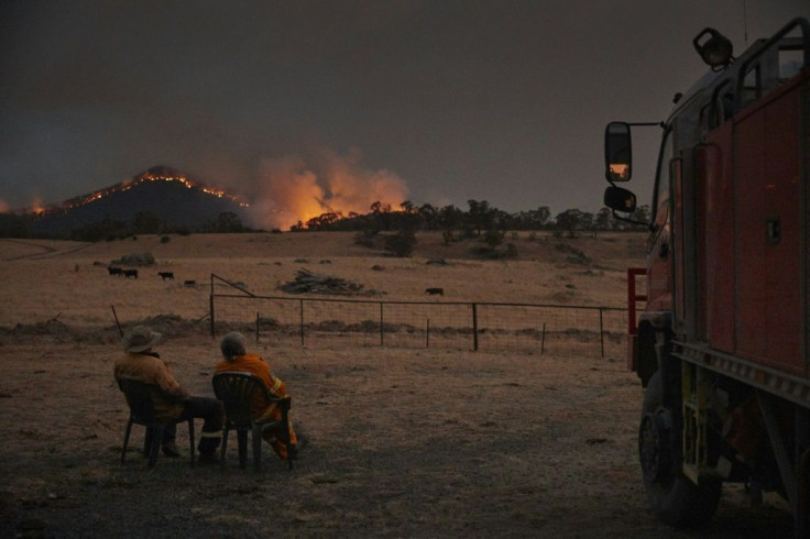 Volunteer firefighters watch as a bushfire rages on the outskirts of the town of Tumbarumba in New South Wales