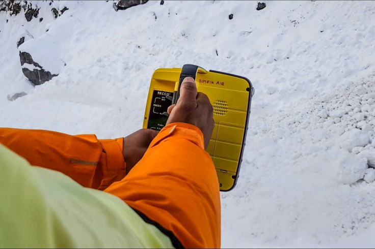 A rescue worker uses an electronic detector to try to locate the missing trekkers