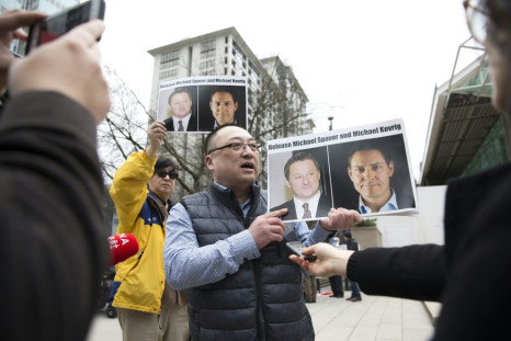 People hold photos of detained Canadians Michael Spavor and Michael Kovrig outside British Columbia Supreme Court, in Vancouver, on March 6, 2019