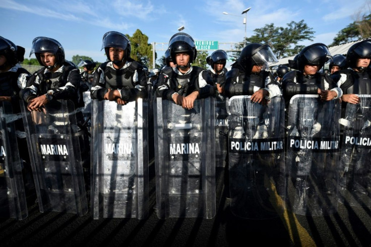 Mexican armed forces stand guard as Central American migrants, travelling on caravan to the US, wait to cross the international bridge that connects Tecum Uman, Guatemala, with Ciudad Hidalgo, Mexico, on January 20, 2020