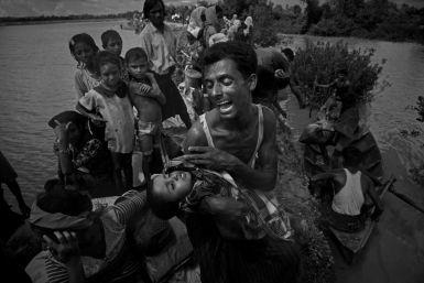 A Rohingya refugee reacts while holding his dead son after crossing the Naf river from Myanmar into Bangladesh on October 9, 2017, about two months after operations by the Myanmar military began
