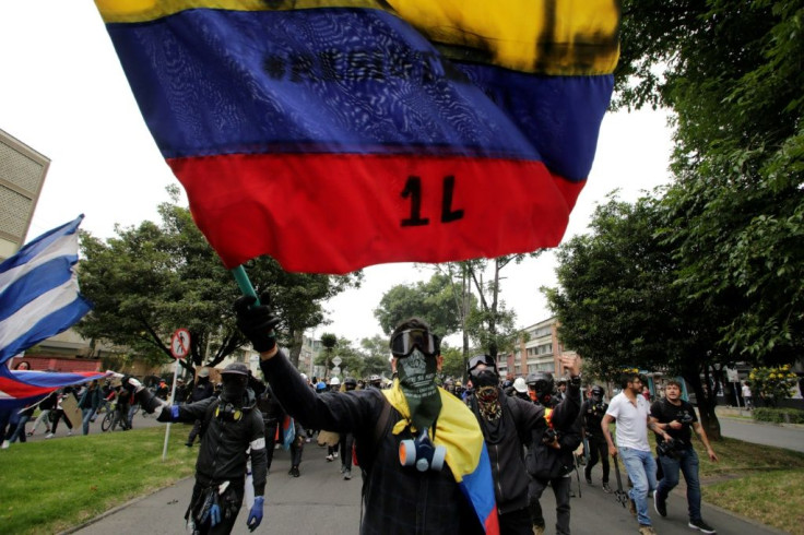 Protestors with their faces covered wave flags during a demonstration against the government of Colombiaâs President Ivan Duque in Bogota