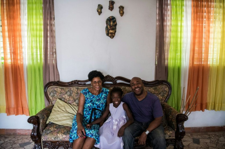 Marie Judith Blaise (L) and Joseph Hyden (R), pose with foster child Myloveda at their home, in Port-au-Prince, Haiti -- where the government of the Americas' poorest country is pushing to deinstitutionalize children