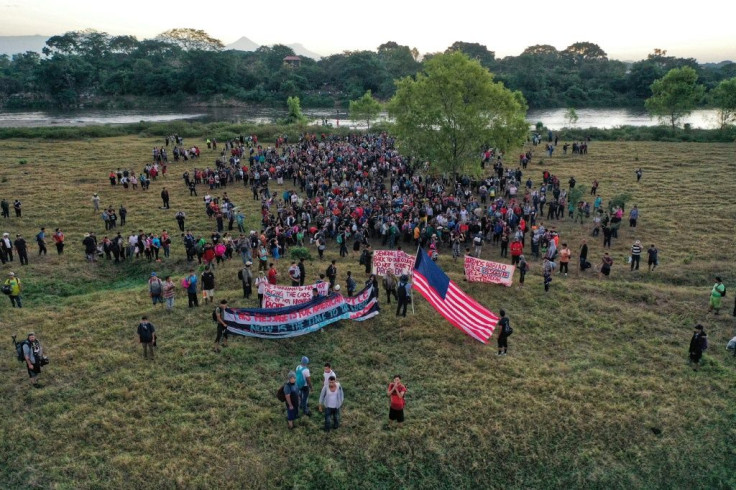Aerial view of Central American migrants - mostly Hondurans heading in a caravan to the US - holding banners and a US flag after crossing the Suchiate River into Mexico from Guatemala