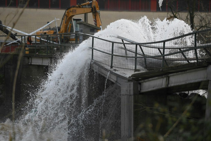 A broken pipe on a damaged bridge flows into the flooded Ter near Girona