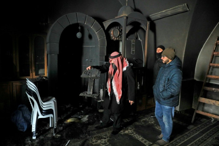 Palestinians inspect the damage from an apparent arson attack on a mosque in Israeli-occupied east Jerusalem