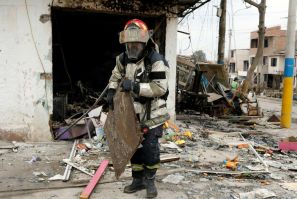 A firefighter sifts through the wreckage of a house destroyed in the blast and subsequent fire