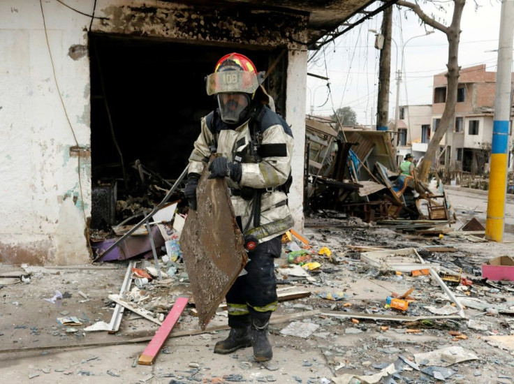 A firefighter sifts through the wreckage of a house destroyed in the blast and subsequent fire