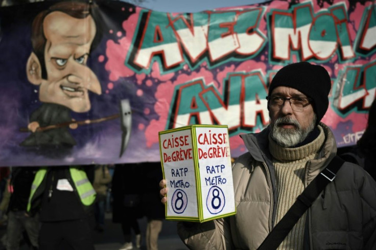 A protester holds a donation box for strikers in front of a banner portraying President Emmanuel Macron during a march against France's pension reform in Paris on Friday.