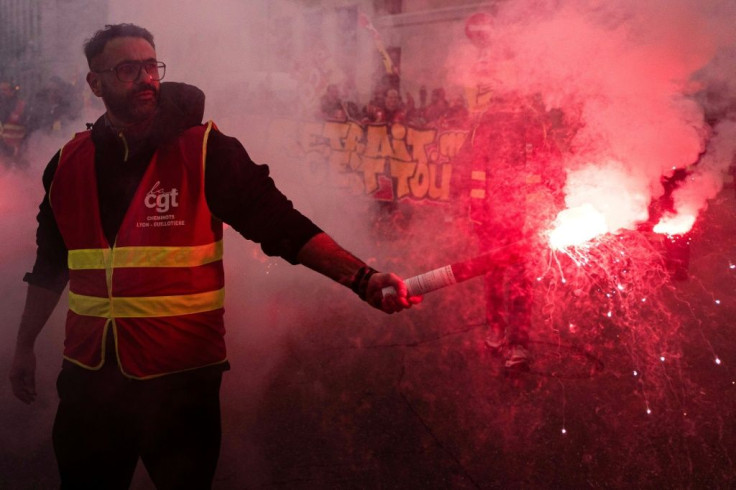 A protester wearing a gilet of the moderate CGT union brandishes a smoke bomb during Friday's demonstration in Lyon, southeast France