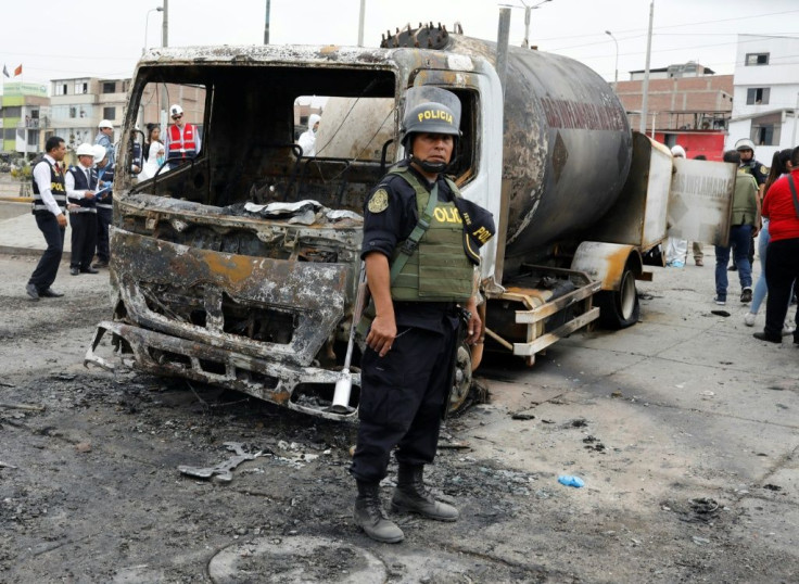 A police officer stands by the wreckage of a gas tanker that exploded in Lima, killing at least eight people and leaving dozens injured