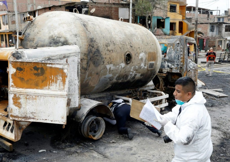 Forensic police inspect the wreckage of a gas tanker that exploded in Lima