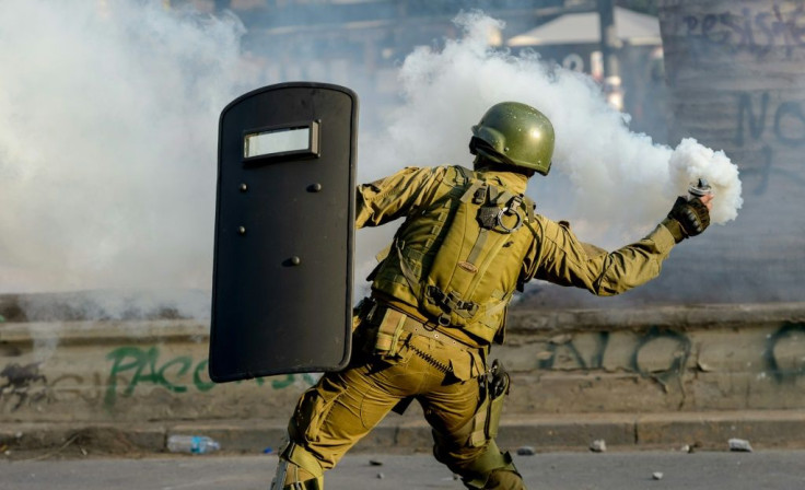 A riot police aims a tear gas canister at demonstrators during clashes which erupted during a protest against the government of Chilean President Sebastian Pinera in Santiago on January 24, 2020