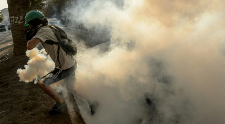 A demonstrator runs away from a tear gas canister thrown by riot police during clashes which erupted during a protest against the government of Chilean President Sebastian Pinera, in Santiago on January 24, 2020