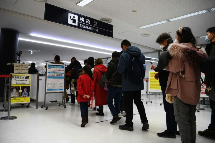 Passengers who arrived on one of the last flights from the Chinese city of Wuhan walk through a health screening station at Narita airport in Chiba prefecture, outside Tokyo