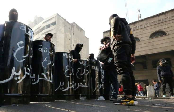 Anti-government protesters wielding protective shields fashioned out of oil drums defend their positions on Baghdad's Al-Sinek bridge as other protest hubs are cleared