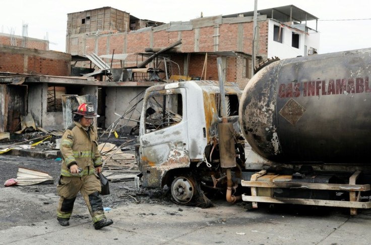 A fireman walks past the tanker truck that exploded in a Lima neighborhood on January 23, 2020, killing several people and igniting houses and cars