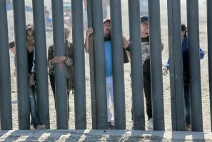 Honduran caravan members look through through a fence at the US-Mexico border in San Ysidro, California in November 2018