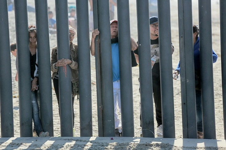 Honduran caravan members look through through a fence at the US-Mexico border in San Ysidro, California in November 2018