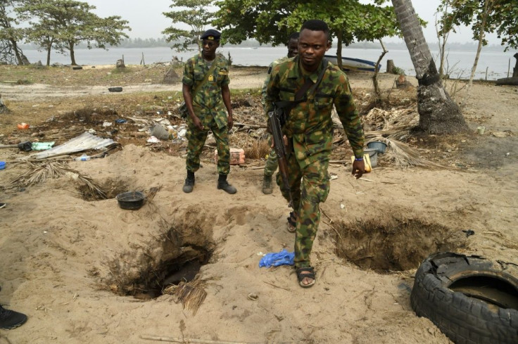 The ground is pockmarked with holes where residents have dug down to pipelines, some filled with shiny oil and water