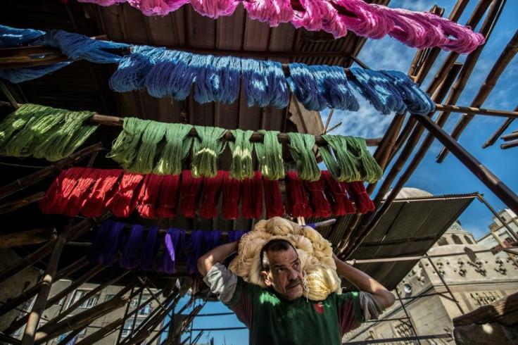 Mohammad Kamal, 59, a worker at Salama Mahmoud Salama's dye workshop, carries yarn to hang out to dry
