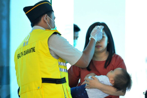 An Indonesian health official checks the temperature of passengers at the airport in Palu, Central Sulawesi. Indonesia has not reported any confirmed infections so far