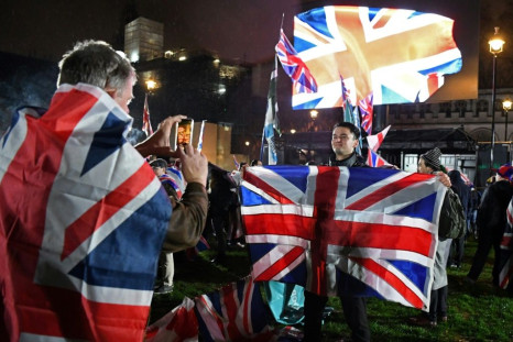 A Brexit supporter poses for a photograph with a Union flag as he waits for the festivities to begin in London on January 31, 2020, the day that the UK formally leaves the European Union