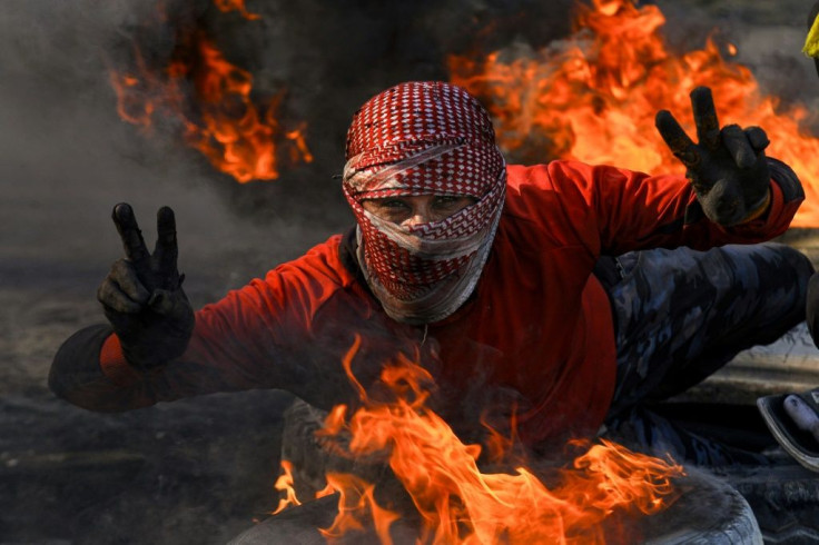 An Iraqi protester flashes the victory sign in the holy city of Najaf where demonstrators blocked roads with burning tyres to protest against the nomination of Mohammad Allawi as the country's new prime minister