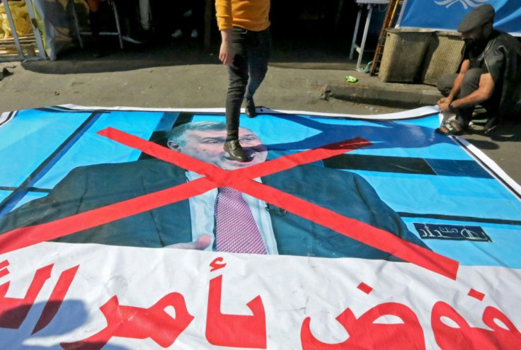 An Iraqi anti-government demonstrator step on a poster bearing the portrait of prime minister-designate Mohammad Allawi in Baghdad's Tahrir square