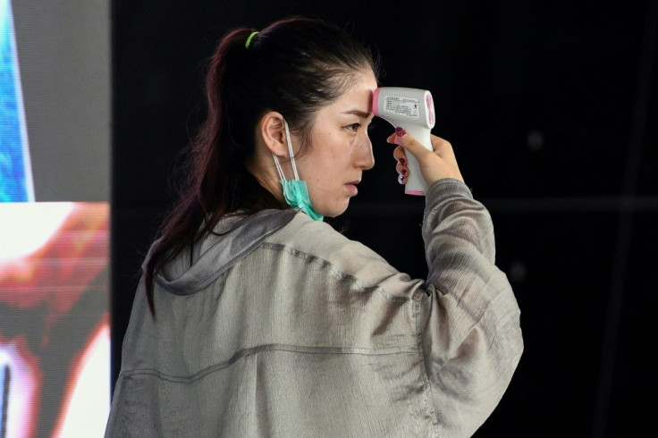 A passenger checks herself with a digital infrared thermometer at Kuala Lumpur International Airport