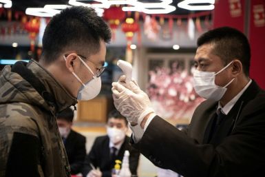 Security personnel check the temperature of shoppers at Hema, an Alibaba supermarket in Hangzhou, the latest city to face restrictions in a bid to halt the spread of the novel coronavirus
