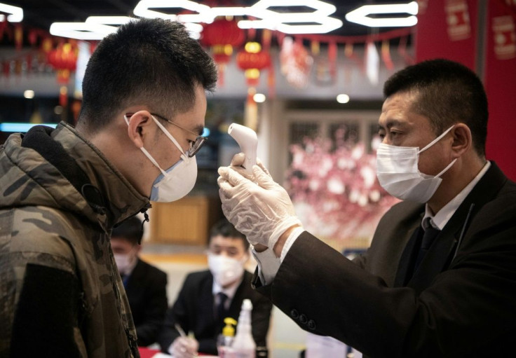 Security personnel check the temperature of shoppers at Hema, an Alibaba supermarket in Hangzhou, the latest city to face restrictions in a bid to halt the spread of the novel coronavirus