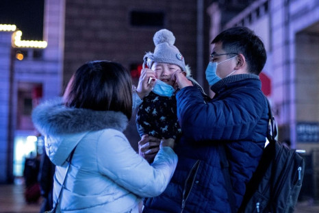 Parents put a protective mask on their baby outside Beijing railway station ahead of the Lunar New Year. State media has reported that a baby tested positive for the virus just 30 hours after being born