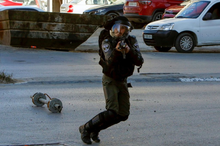 An Israeli border guard aims his rifle towards Palestinian protesters during a raid near the West Bank town of Bethlehem
