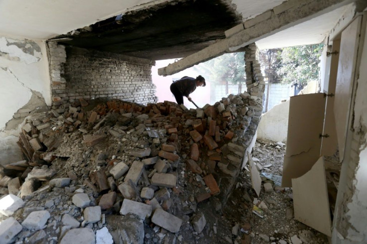 Vjollca Mesiti rummages through the ruins of her bakery to salvage items in Thumane, one of the hardest hit areas by the most destructive quake in four decades