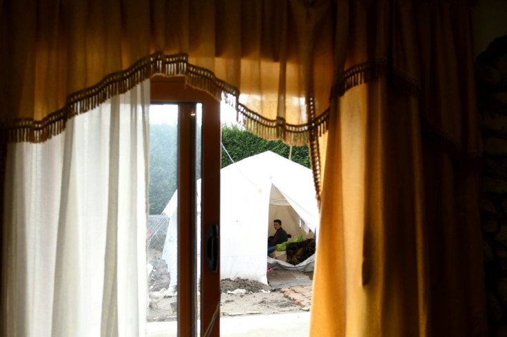 Vladimir Leka, 16, watches TV in a tent next to his damaged house in Thumane, northwest of Tirana