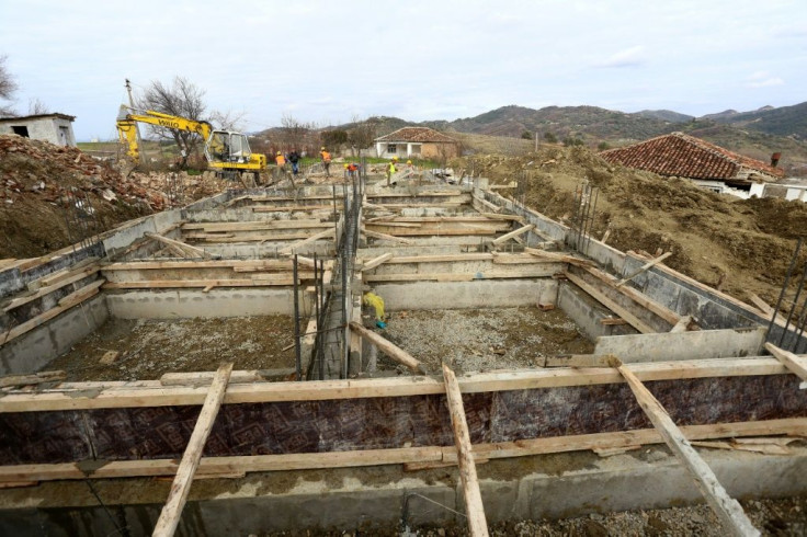 Construction workers toil on the site of three houses destroyed in the village of Likesh, where an NGO is rebuilding homes with funds raised from Albanians living abroad